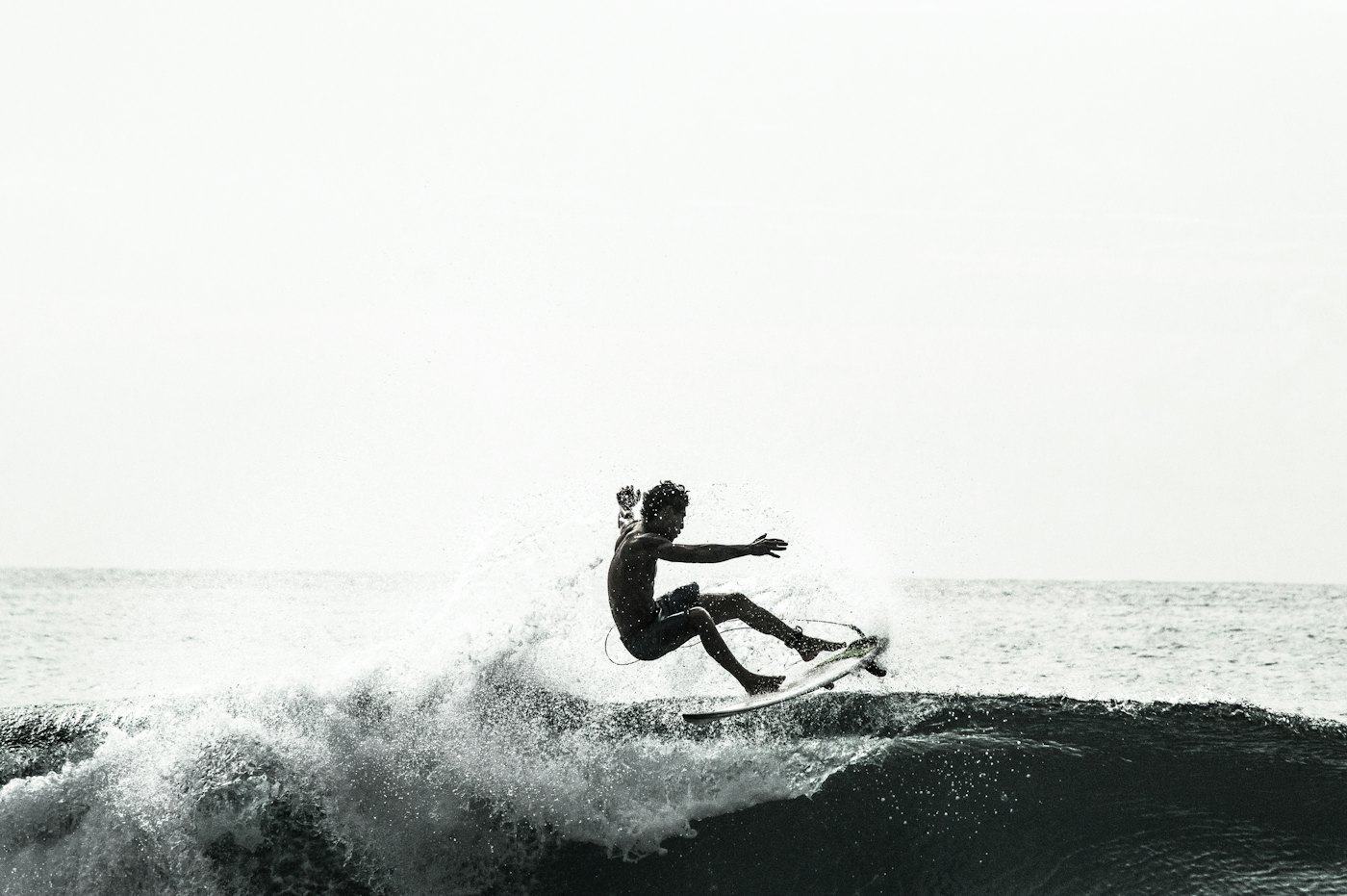 Surfista fazendo uma manobra em uma onda, em preto e branco
