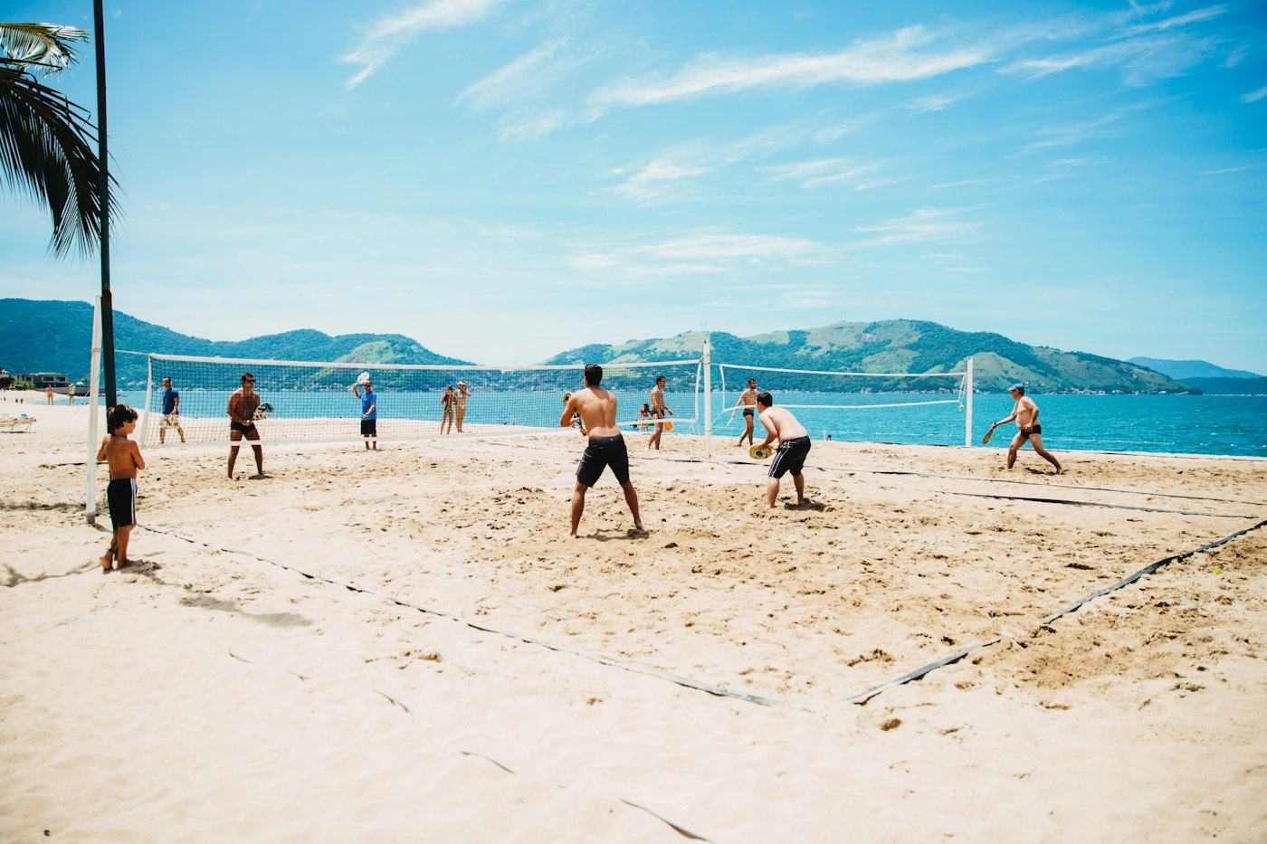 Pessoas jogando vôlei de praia na areia em um dia de sol